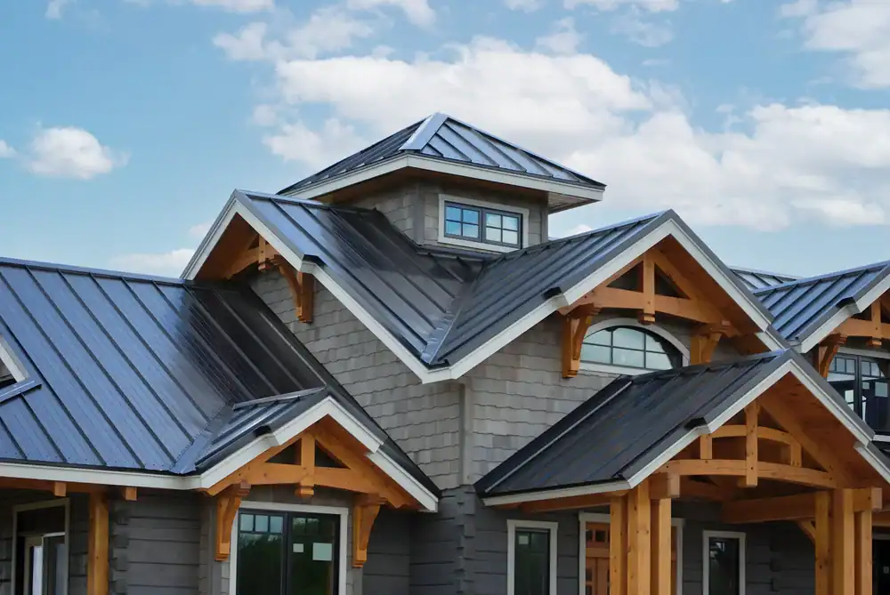 Modern house with a dark metal roof, wooden beams, and gray siding under a blue sky with scattered clouds. Multiple roof peaks and windows showcase the work of a skilled roofer in Jasper County, TX, highlighting unique architectural design.